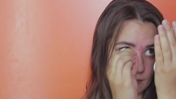 A girl with brown eyes plucks her eyebrows with tweezers. Close-up — Stock Video