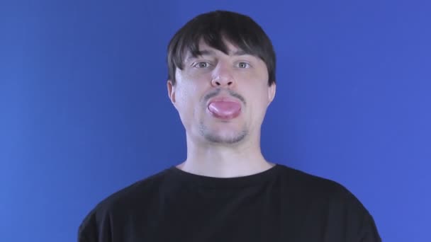 Mladý muž žvýká žvýkačku a vtipně fouká bublinu — Stock video