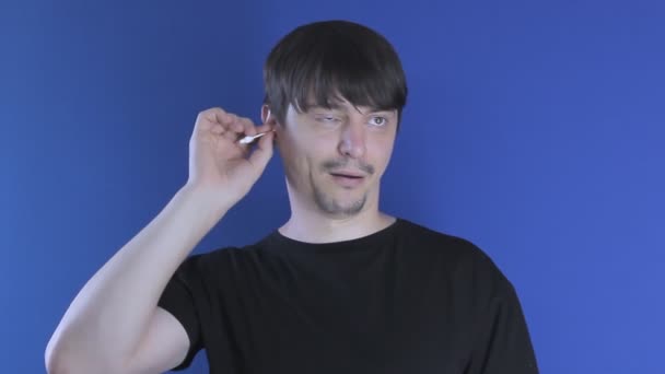 A man cleans his ears with a cotton swab and pulls out earwax — Stock Video