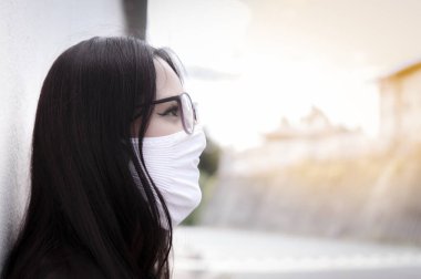 Gün batımında ufka bakan maskeli bir kız.