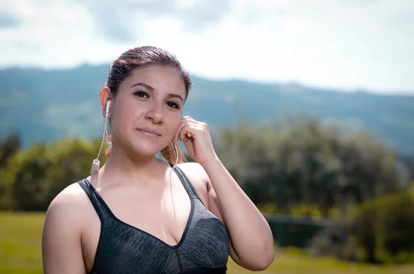 portrait of young latina woman putting on her headphones to perform an exercise routine