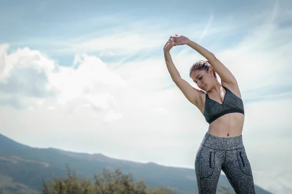 Latina woman stretching her muscles in the morning with the background of mountains