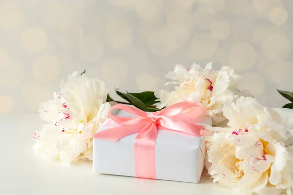 Caja de regalo y peonías sobre fondo blanco — Foto de Stock