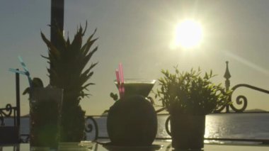 Arka planda günbatımı olan bir masada birden fazla kokteyl.