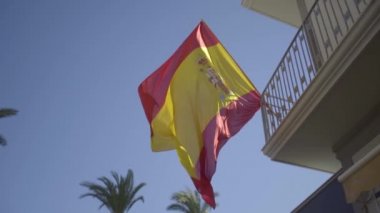 Mavi gökyüzü rüzgarda dalgalanan İspanyol bayrağının yavaş çekim görüntüsü.
