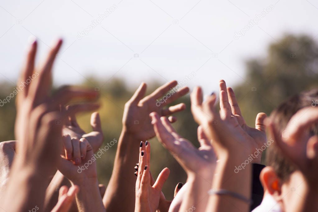 Crowded people hands up at a day time concert.