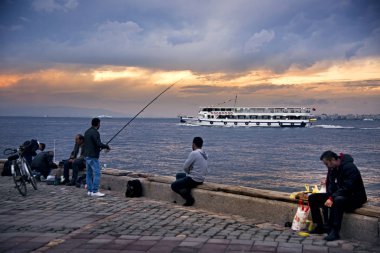 Izmir, Türkiye - 28 Ekim 2017: Izmir Alsancak Viev feribot ve bazı erkekler yakınındaki waters Edge bulutlu hava ile Balık tutma.