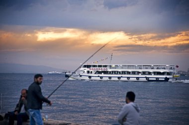Izmir, Türkiye - 28 Ekim 2017: Izmir Alsancak Viev feribot ve bazı erkekler yakınındaki waters Edge bulutlu hava ile Balık tutma.