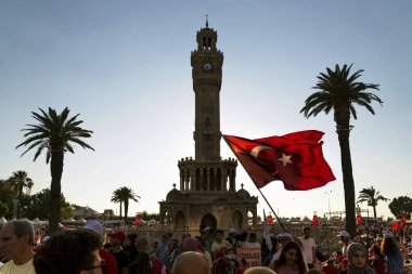 Izmir, Türkiye - 15 Temmuz 2018: Demokrasi Türkiye'de Izmir'in 15 Temmuz günü. Türk bayrakları Konak, Izmir tarihi saat kulesi önünde kare holding ve kişilere.