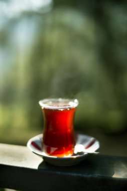 Doğrudan güneş ışığı ve açık altında yeşil bir arka plan üzerinde Türk çayı.