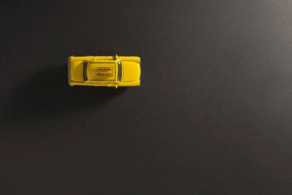 長いと側面の影で黒の背景に黄色のおもちゃのタクシー車の上から見る — ストック写真