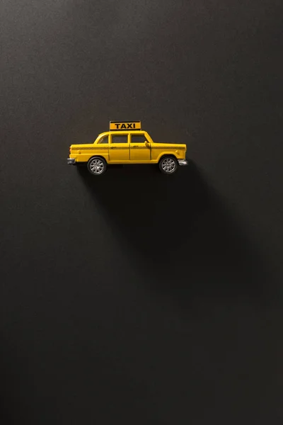 長いと側面の影で黒の背景に黄色のおもちゃのタクシー車のサイドビュー — ストック写真