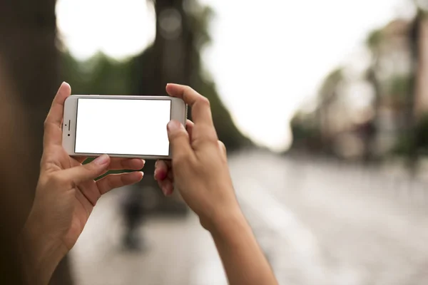 Looking at blank screen of a  smartphone in the hand on the street.