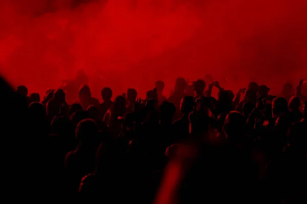 Concert field, crowded people under the red stage lights.