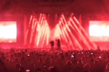 Konser alanı, kalabalık insan ve sahne ışıkları.