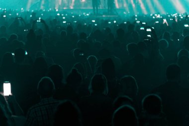 Konser alanı, kalabalık insan ve sahne ışıkları.