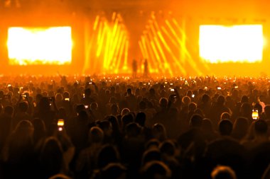 Konser alanı, kalabalık insan ve sahne ışıkları.