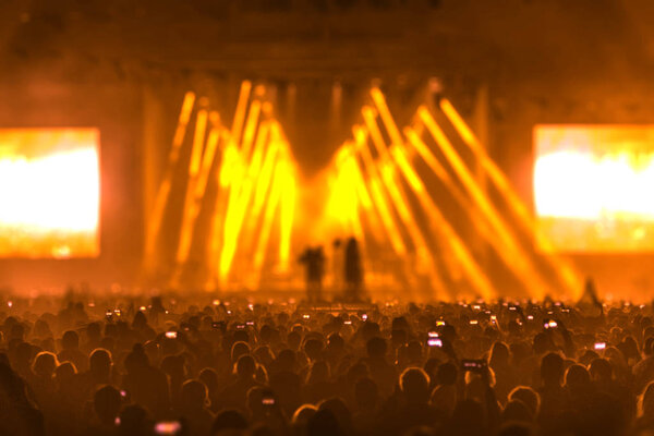 Concert field, crowded people and stage lights.