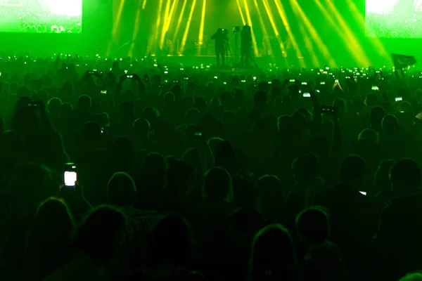 Concert field, crowded people and stage lights.