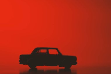 Canlı kırmızı arka planda siluet oyuncak araba.