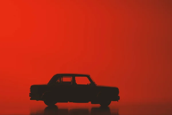 Silhouet Speelgoed Auto Een Levendige Rode Achtergrond — Stockfoto