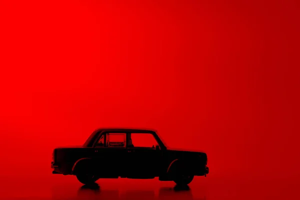 Silhouet Speelgoed Auto Een Levendige Rode Achtergrond — Stockfoto
