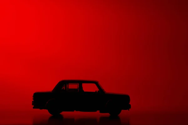 역동적 빨간색 배경에 실루엣 장난감 자동차 — 스톡 사진