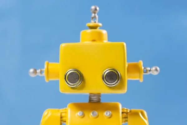 Portrait of a Cute, yellow, handmade robot on a blue background.