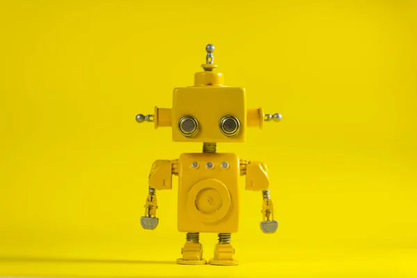 Cute, yellow, handmade robot on a yellow background.