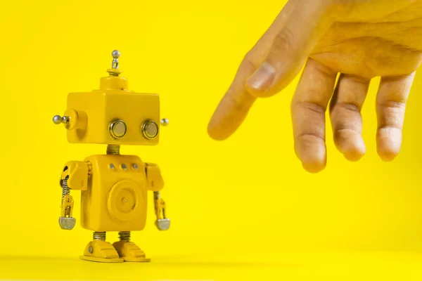 Cute, yellow, handmade robot on a yellow background.