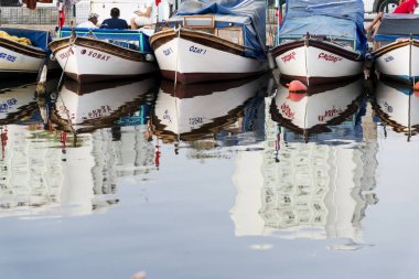Izmir, Türkiye - 12 Ağustos 2018: Çeşitli balıkçı tekneleri yansıması ile belgili tanımlık sığınak içinde park edilmiş. Bostanlı balıkçı barınağı Izmir Türkiye.