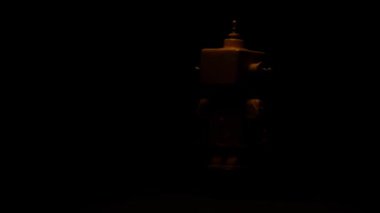 Siyah arka planda ve yüksek kontrast ile yüzen ve dönen sarı robot.