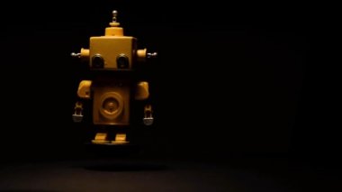 Siyah arka planda ve yüksek kontrast ile yüzen ve dönen sarı robot.