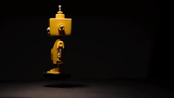 Robot Amarillo Flotante Giratorio Sobre Fondo Negro Con Alto Contraste — Vídeo de stock