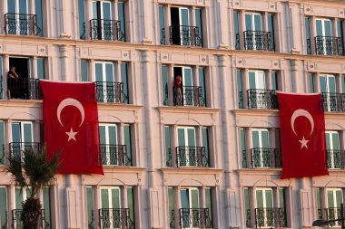 İki kişi ile bir binada asılı Türk bayrakları.