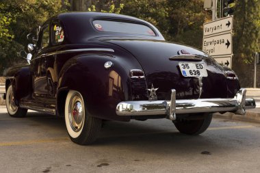 Koyu kırmızı siyah bir Plymouth Deluxe 'un arka görüntüsü.