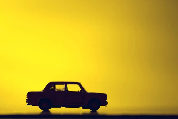 Coche de juguete de silueta sobre un fondo rojo vibrante . — Foto de Stock