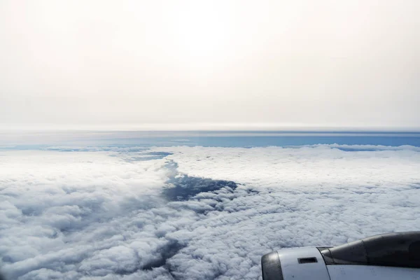 Nuvens de uma janela de um avião comercial com mar . — Fotografia de Stock