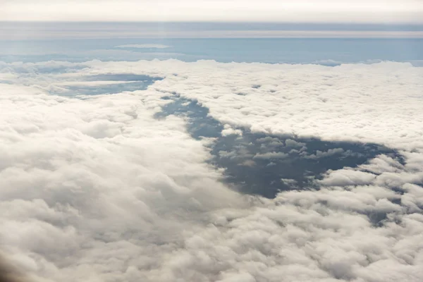 Σύννεφα από ένα παράθυρο εμπορικού αεροπλάνου με θάλασσα. — Φωτογραφία Αρχείου