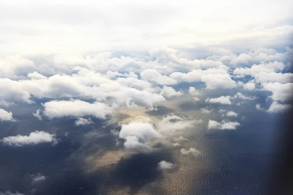 Nuvens de uma janela de um avião comercial com mar . — Fotografia de Stock