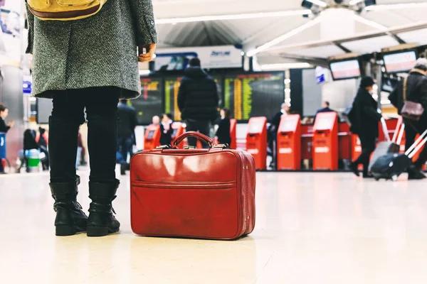 Donna con stivali, cappotto e una borsa rossa in aeroporto . — Foto Stock