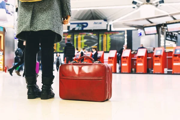 Donna con stivali, cappotto e una borsa rossa in aeroporto . — Foto Stock