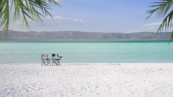 白い砂とターコイズ色の水を持つモルディブのようなサルダ湖は 2つの空の椅子とヤシの葉がシーンに ブルドゥール トルコ — ストック動画