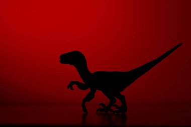Kırmızı renkli arka planda bir dinozor silueti.