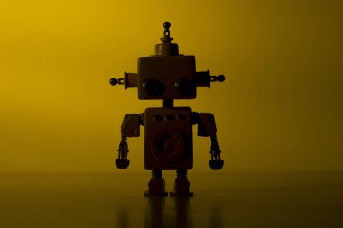 Sarı arka plan üzerinde sevimli bir robot silueti.