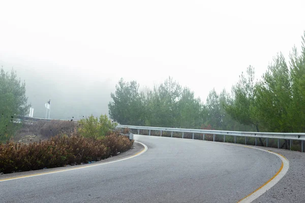 在多雾的天气里弯弯曲曲的道路的斜坡. — 图库照片