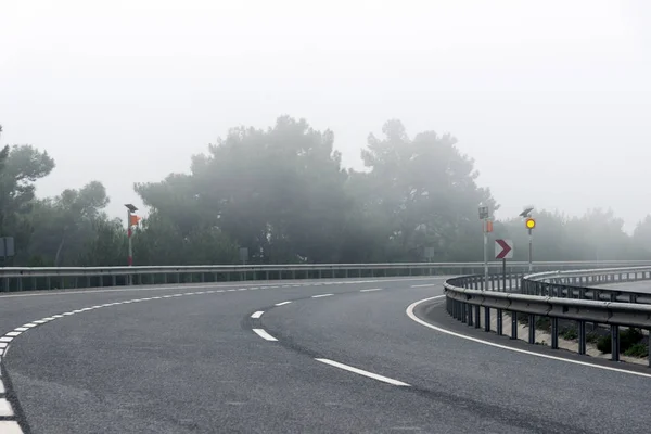 Buigen weg op de snelweg met mist in de ochtend. — Stockfoto