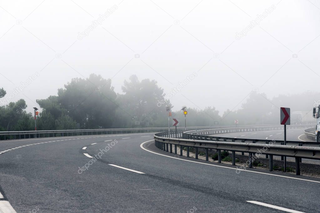 Bending road on Highway with fog in the morning.