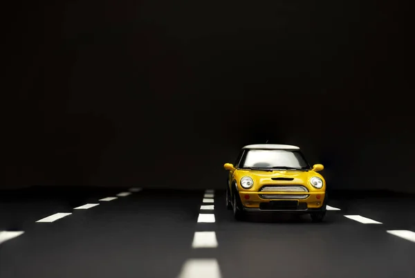 Yellow Toy Model Car on a black background and Three Lane road. — Stock Photo, Image