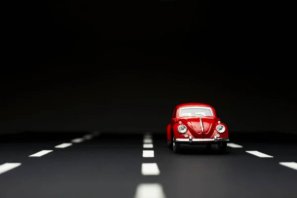 Close up tiro de um carro de brinquedo vermelho em uma estrada com faixa de estrada — Fotografia de Stock